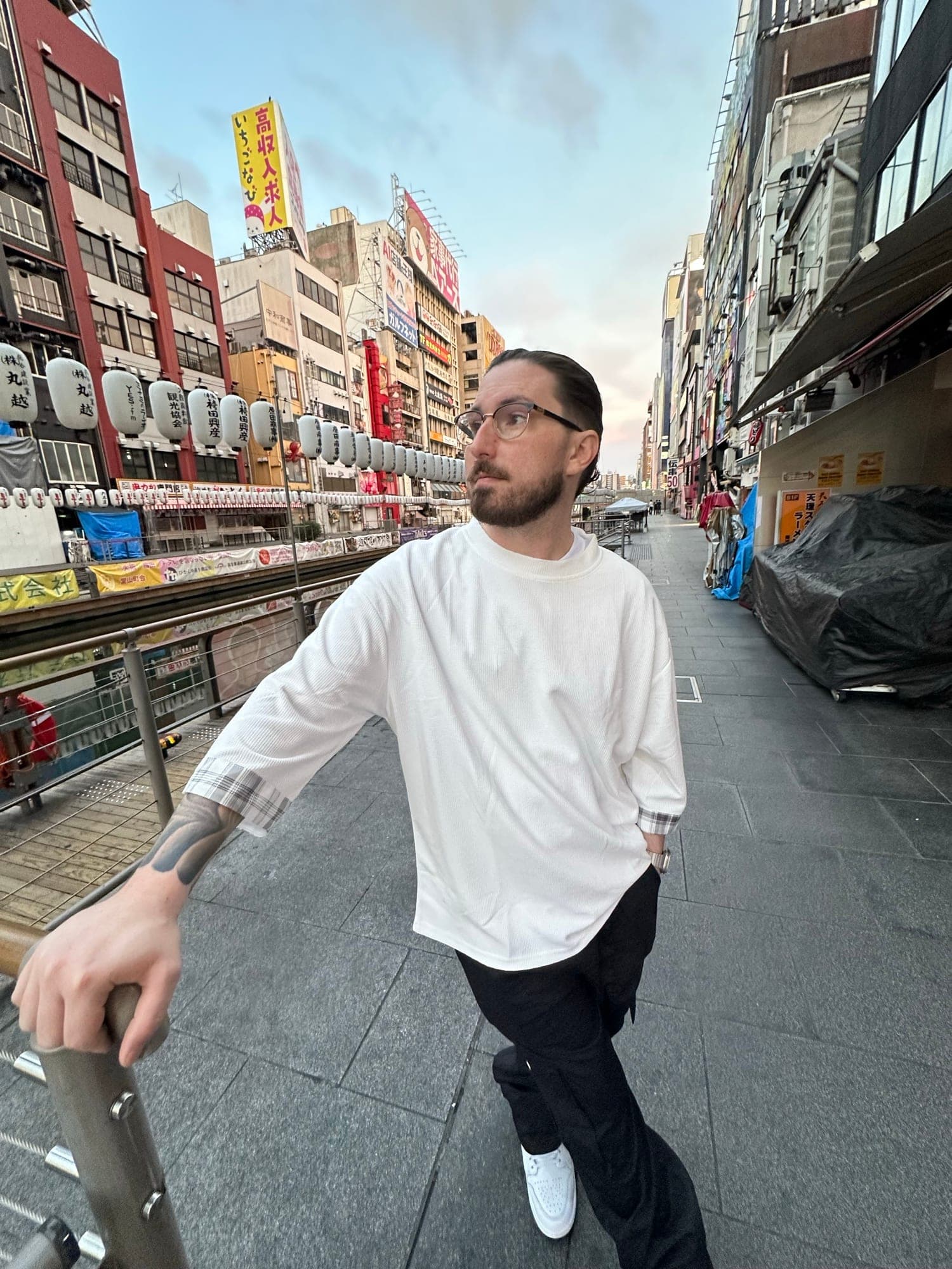Dave in a white tee leaning on a railing beside the Dotonbori canal in Osaka, paper lanterns and shop signs behind him